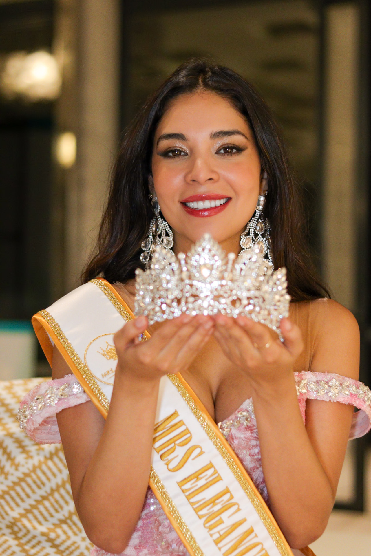 Joven con banda dorada de Mrs Elegance sosteniendo una corona